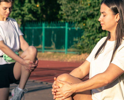pareja de deportistas estirando la rodilla para prevenir lesiones de rodilla como el síndrome fémoro-patelar, también llamado condromalacia rotuliana